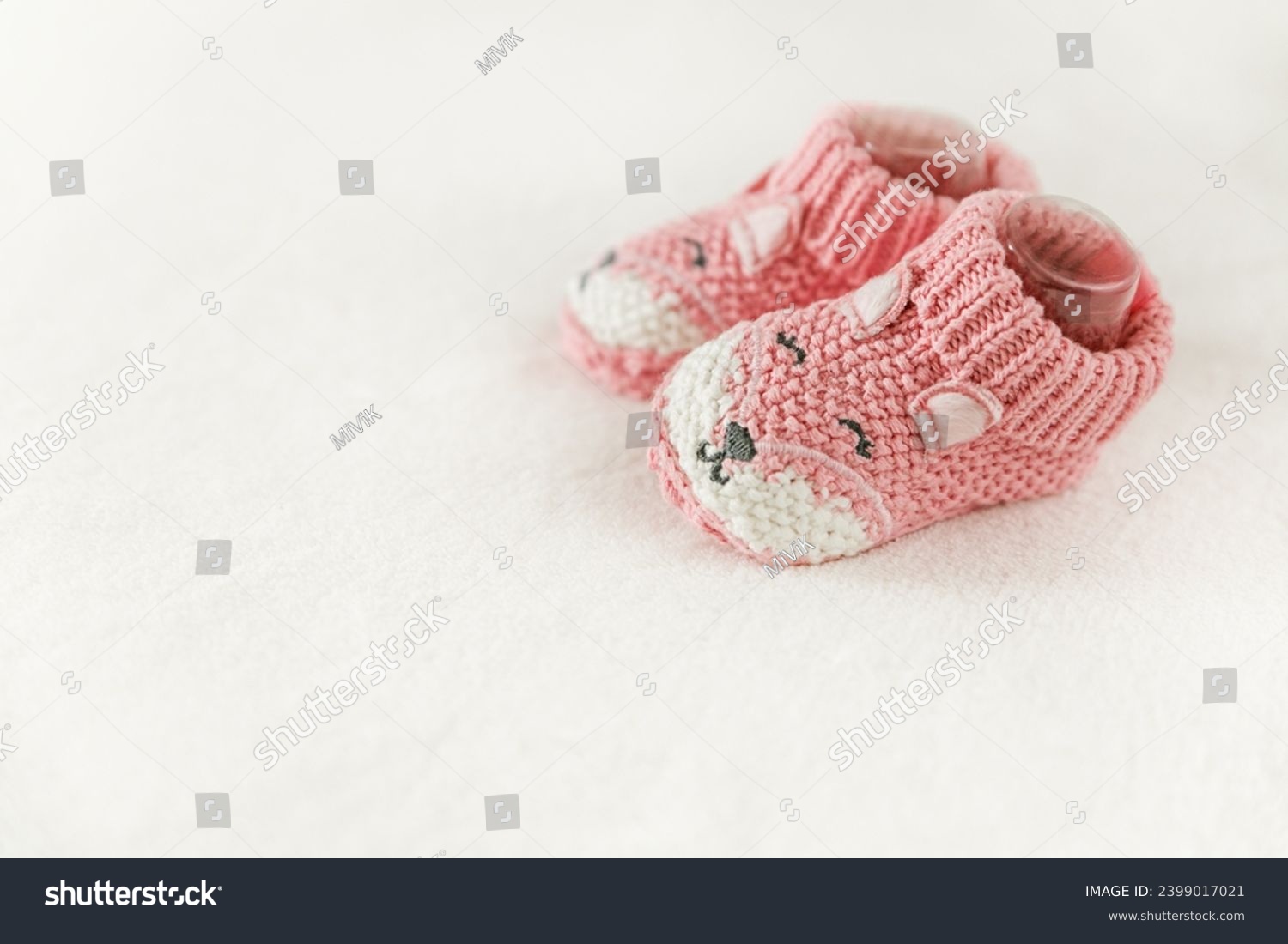 Pink knitted children's shoes on a white background with copy space. Pregnancy and motherhood concept, first birthday banner, handmade socks, baby warm clothes, handmade knitted socks, hobby. #2399017021