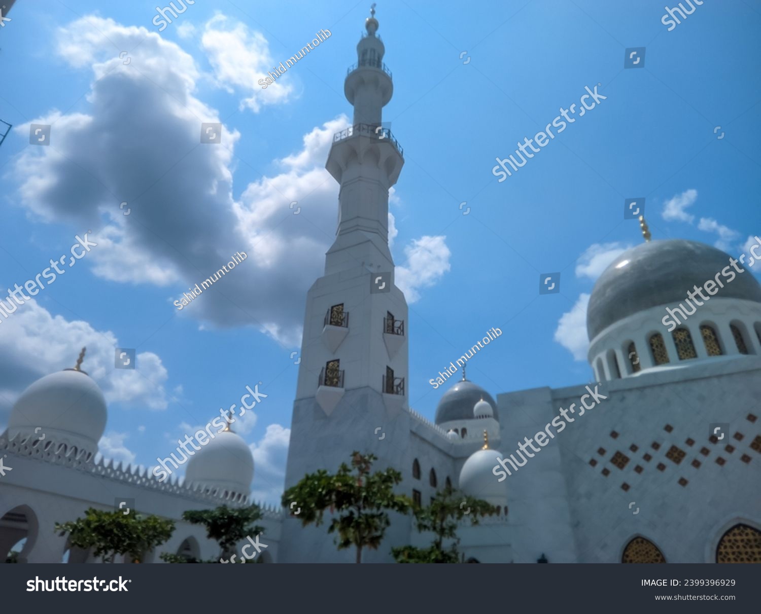 You can see the mosque dome and mosque tower high in the bright blue sky and white clouds of the Syech Zayed mosque building in Solo, Central Java, Indonesia  #2399396929