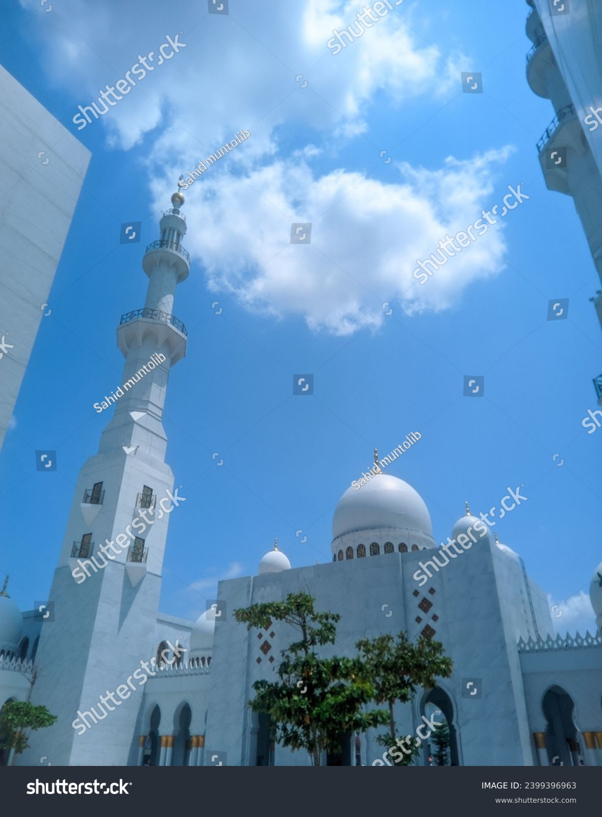 You can see the mosque dome and mosque tower high in the bright blue sky and white clouds of the Syech Zayed mosque building in Solo, Central Java, Indonesia  #2399396963