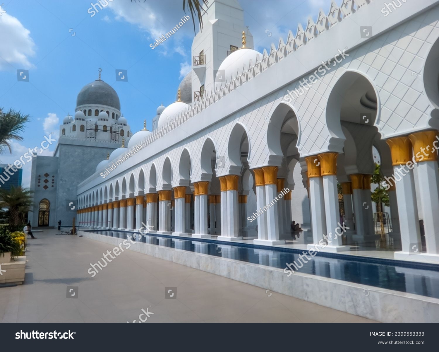The splendor of the Syech Zayed Mosque building in the city of Surakarta, Central Java, is elegant and you can see some leaves from the trees around it and the bright blue sky and white clouds  #2399553333