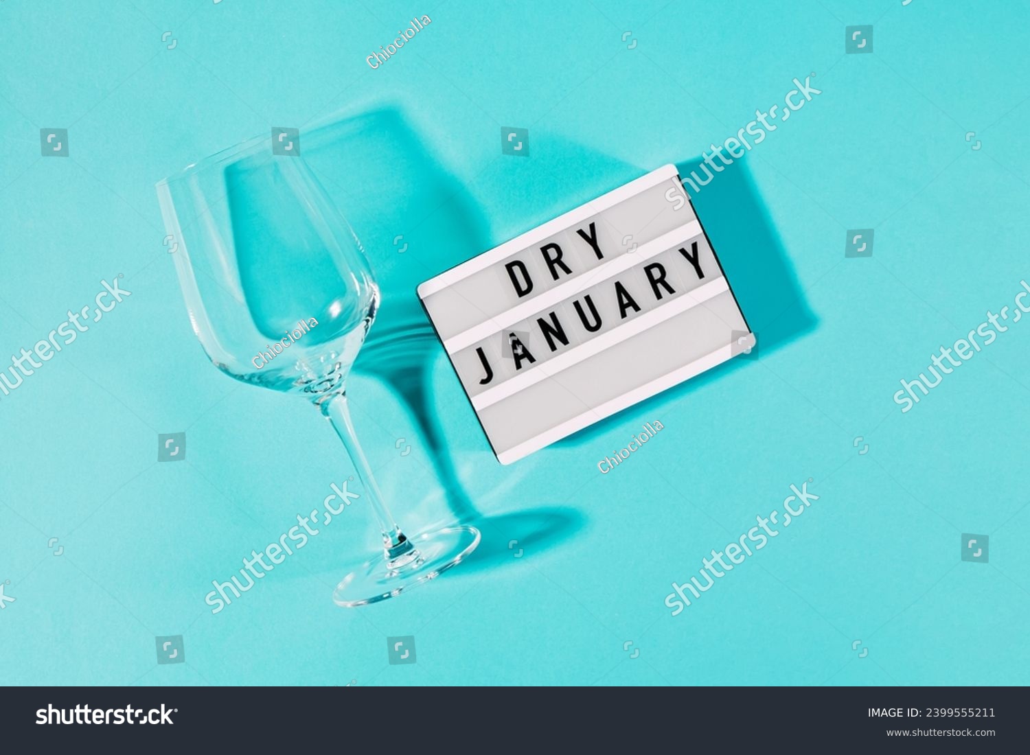 Text Dry January on the decorative lightbox and empty wine glass isolated on blue background, top view #2399555211