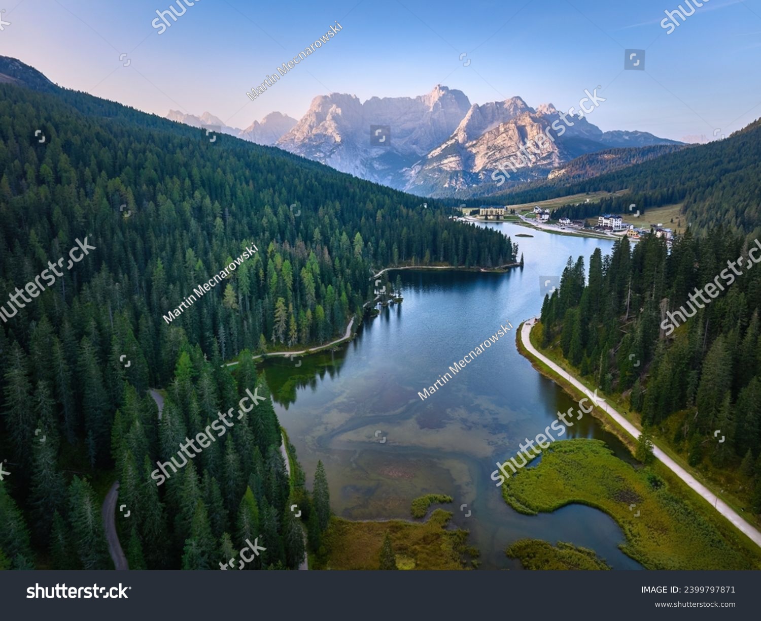 Aerial view of Lago di Misurina  and the panorama of the Dolomites in background. Sunny morning, blue sky, view across the lake and hiking paths.  #2399797871