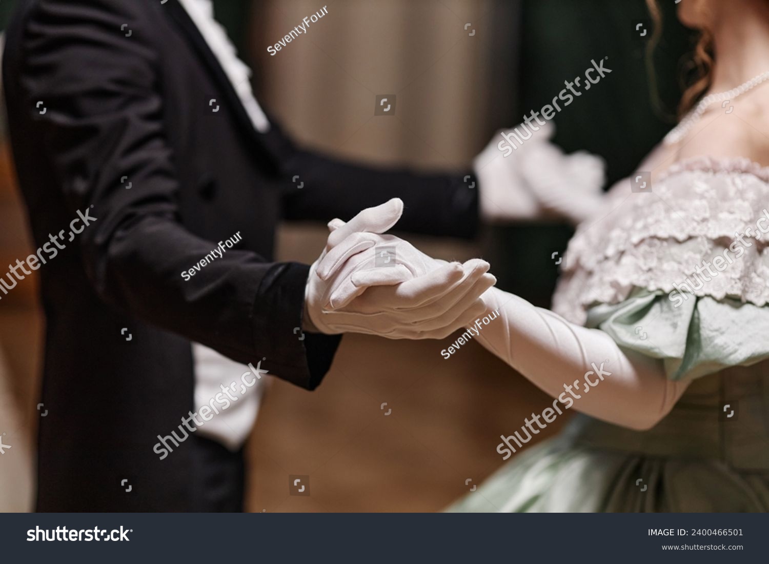 Close up of historical young couple dancing waltz together in ballroom, focus on gloved hands, copy space #2400466501