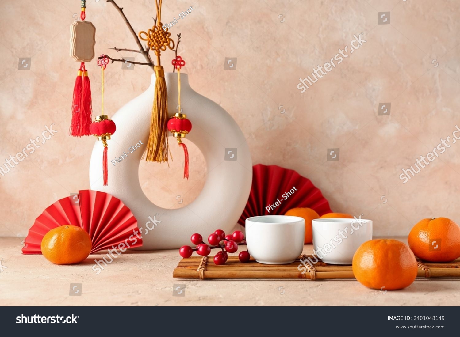 Vase with oriental symbols, cups and mandarins on table against beige grunge background. New Year celebration #2401048149