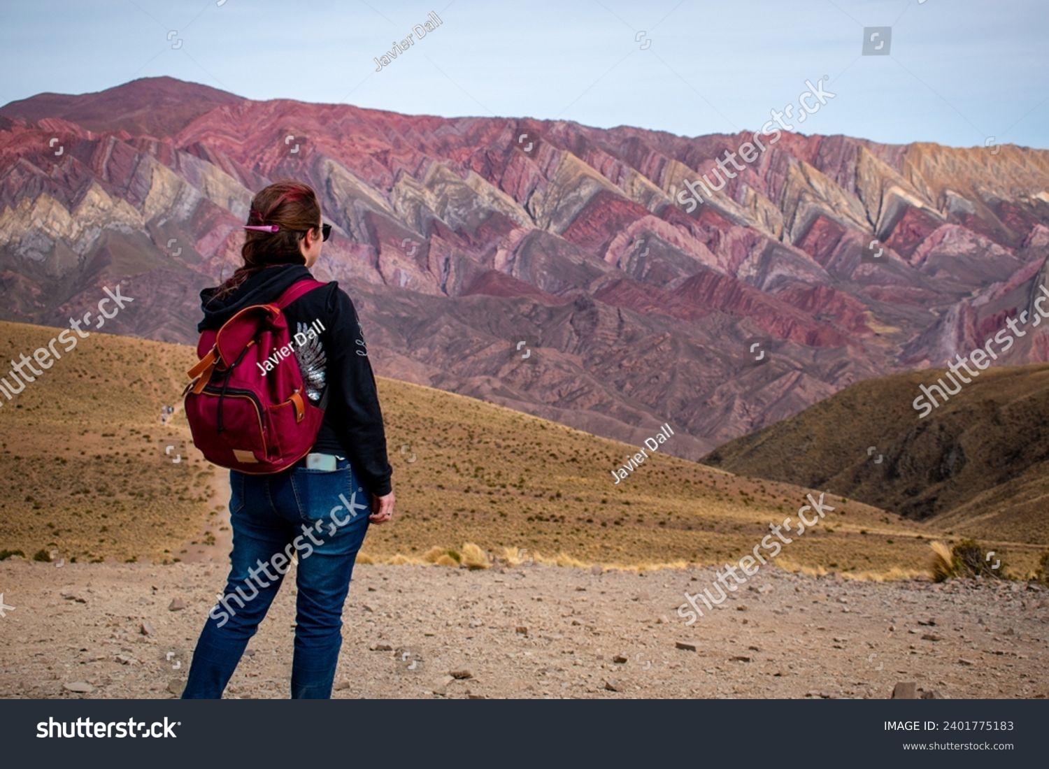 Tourist exploring Argentina. Young woman enjoying the views in El Hornocal, Jujuy, Argentina. Alone person on vacation in the north of Argentina. Tourist touring El Hornocal in Argentina.  #2401775183
