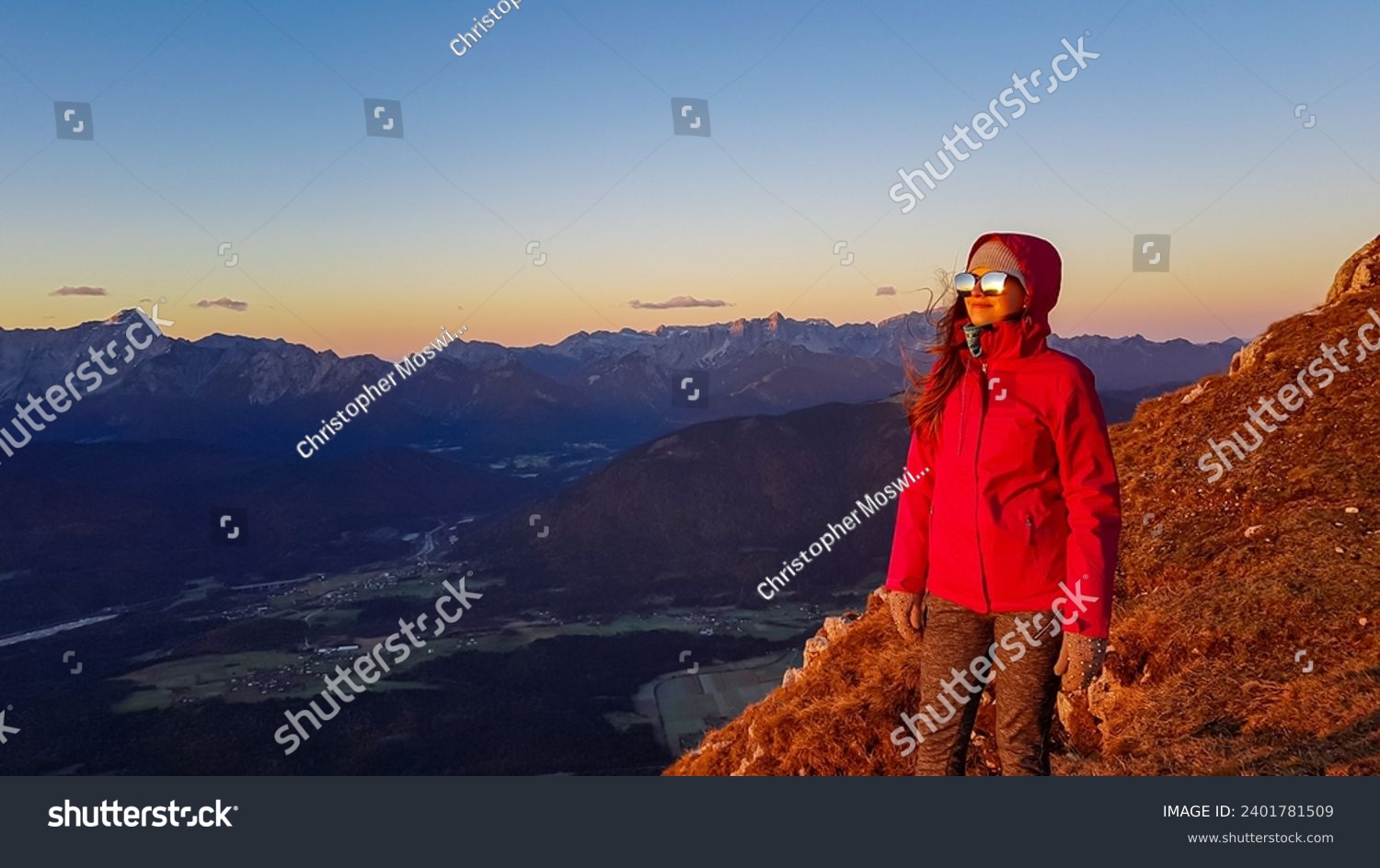 Happy woman enjoying scenic view during sunrise from Dobratsch, Villacher Alps, Carinthia, Austria, Europe. Looking at mountain ranges Julian Alps and Karawanks. Sunbeams reflecting in sunglasses. #2401781509