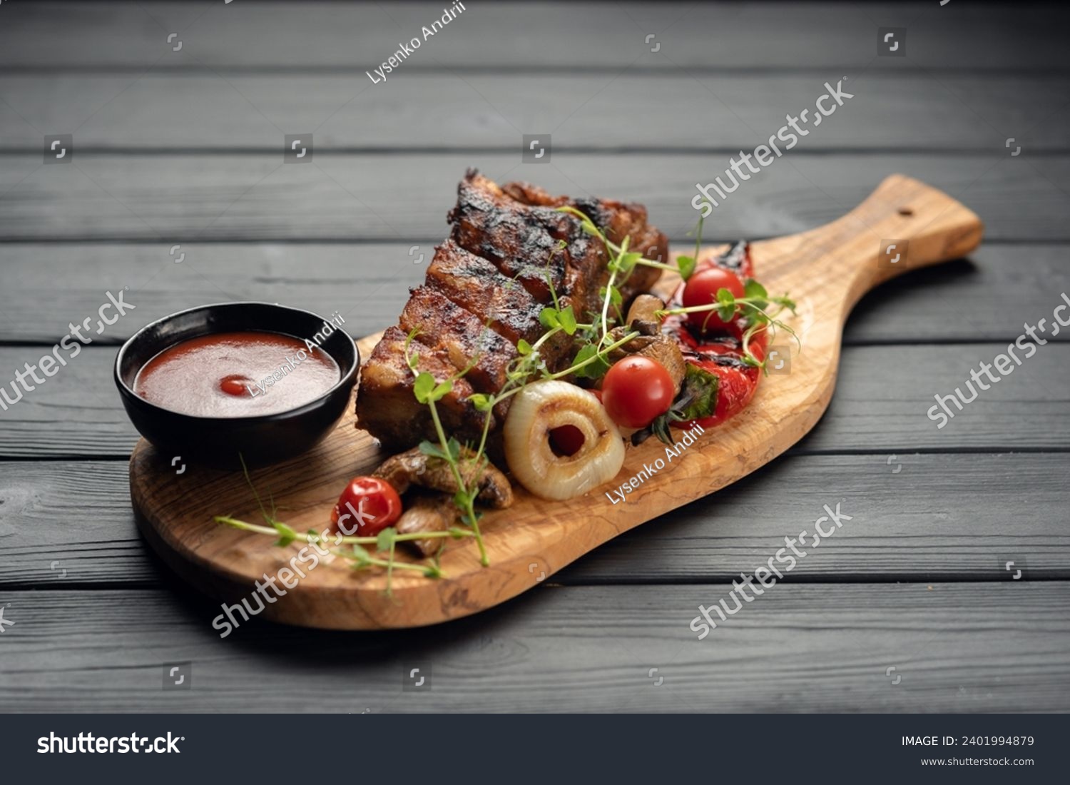 hot grilled spare ribs from a summer BBQ served with a grilled vegetables and sauce on an old vintage wooden cutting board. Copy space #2401994879