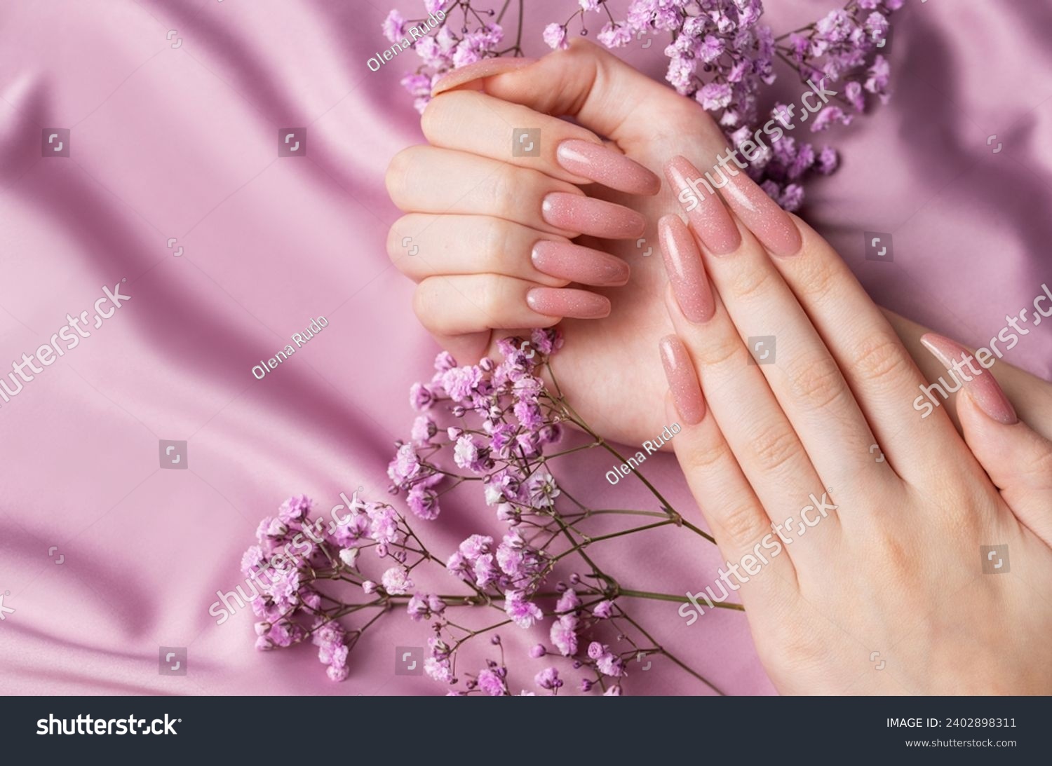 Female hands with beautiful manicure  with gypsofila flowers on pink silk #2402898311