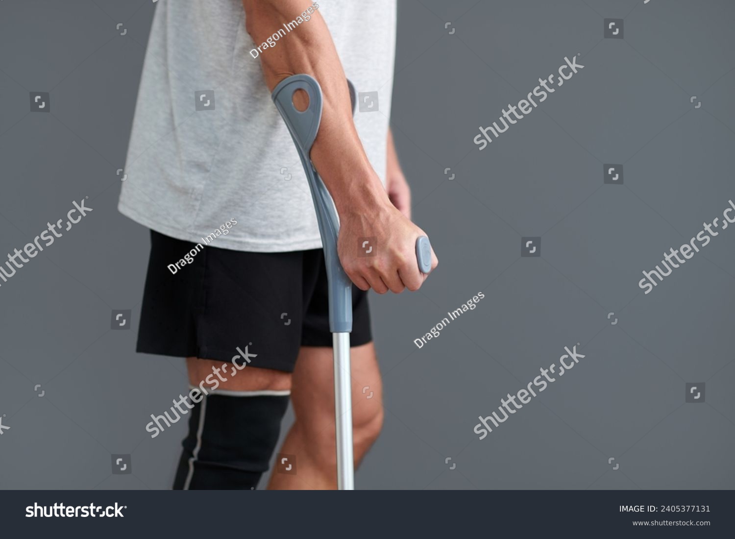Cropped image of man with injured leg leaning on crutch when walking #2405377131