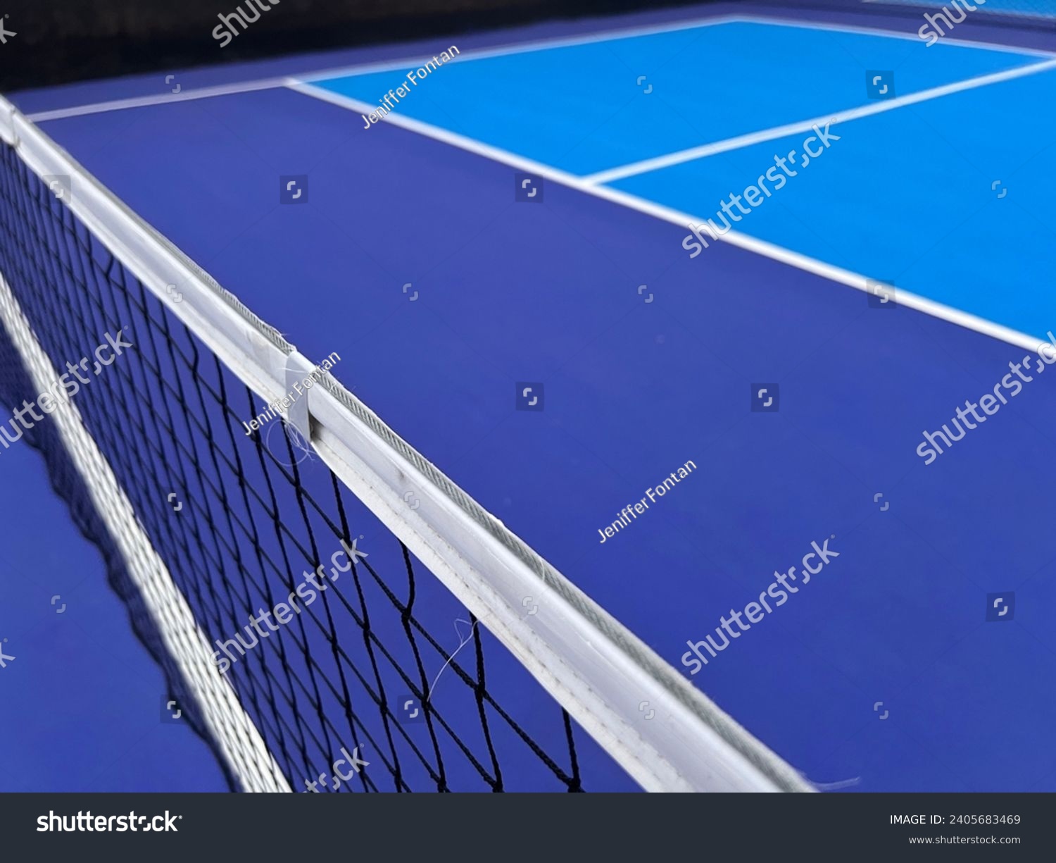 Pickle ball court in blue and white colors with net in black and white. Wide view of a pickleball court #2405683469