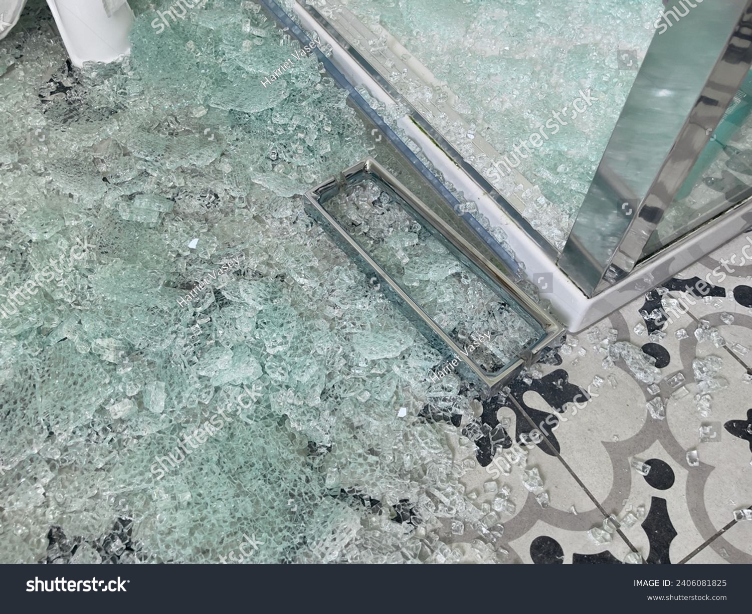 Broken glass shower door with chrome handle in a tiled bathroom #2406081825