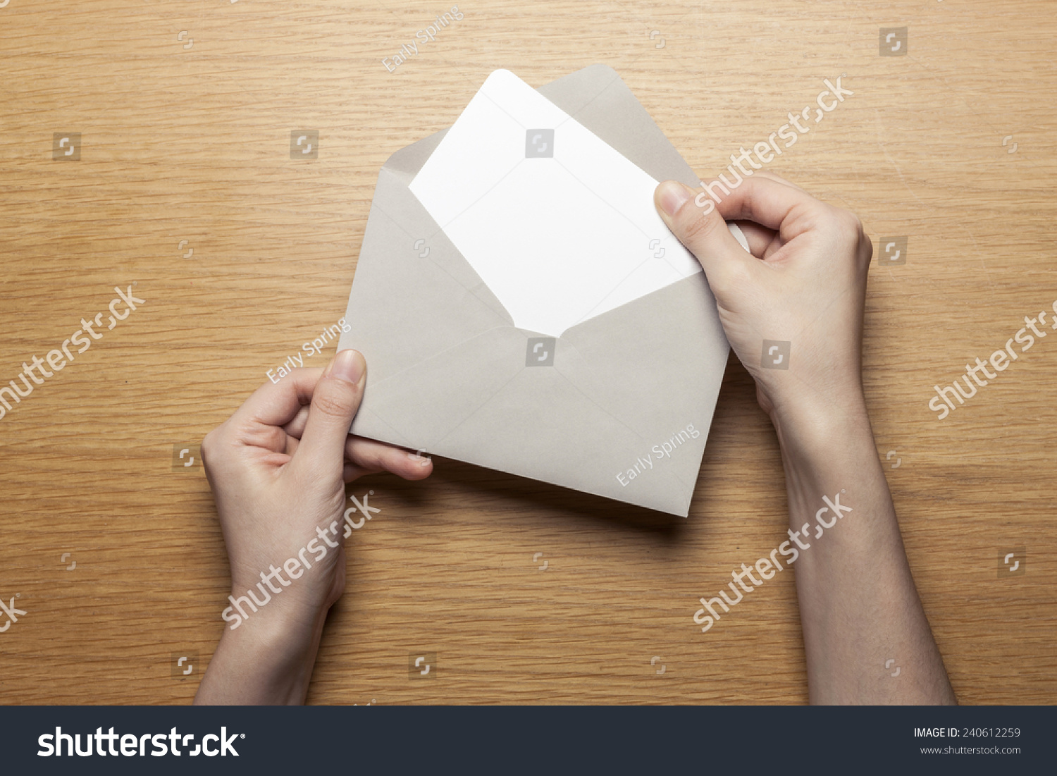 A female(woman) hand hold(open) a envelope and post card on the wood desk, top view at the studio.  #240612259