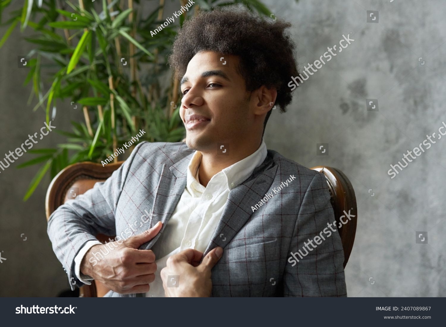 Side view of arrogant narcissistic self-centered african american businessman sitting in leather armchair adjusting his gray stylish elegant jacket, feeling proud of his business project and success #2407089867