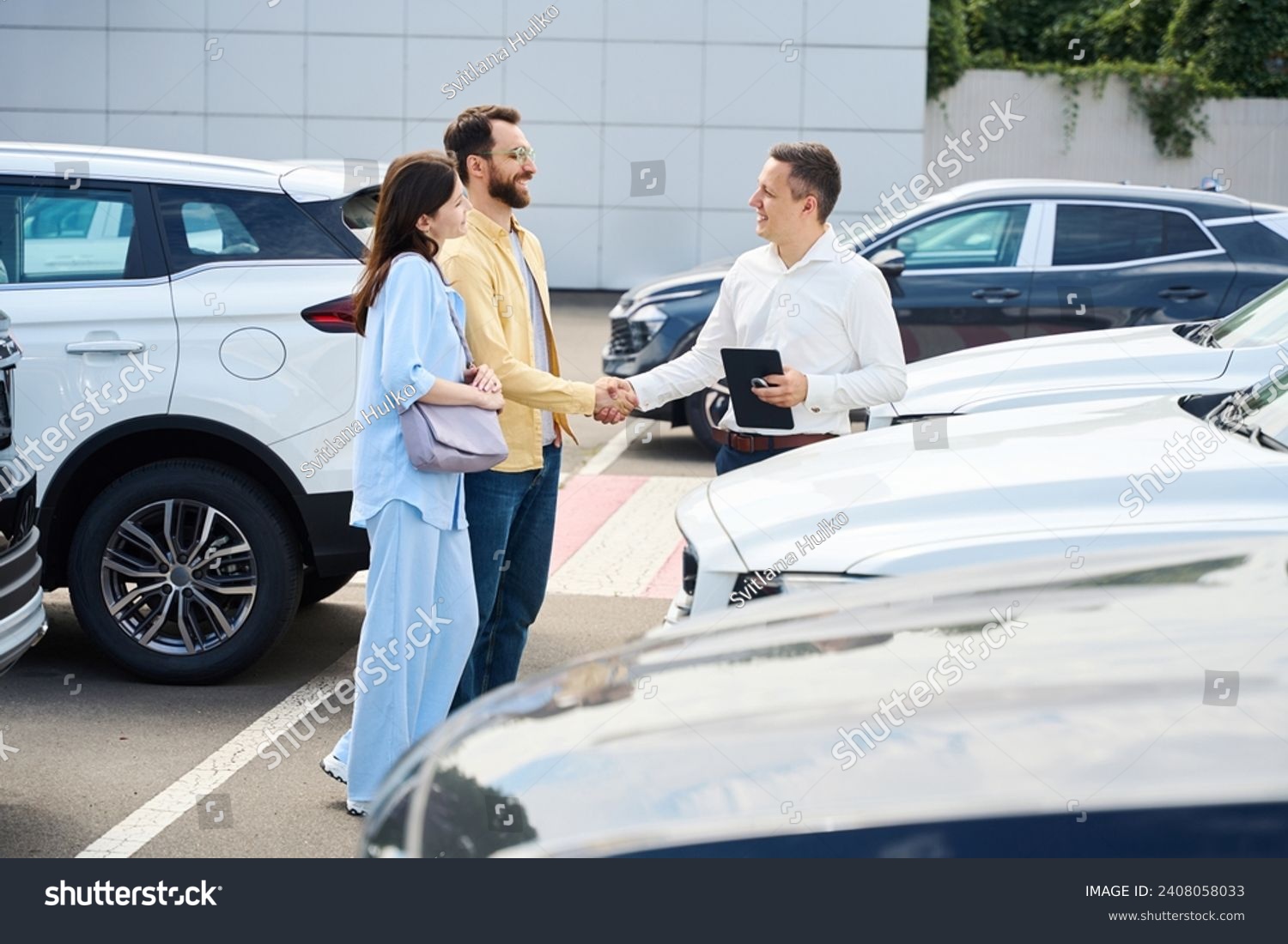 Car dealership employee communicates with couple of clients before test drive #2408058033