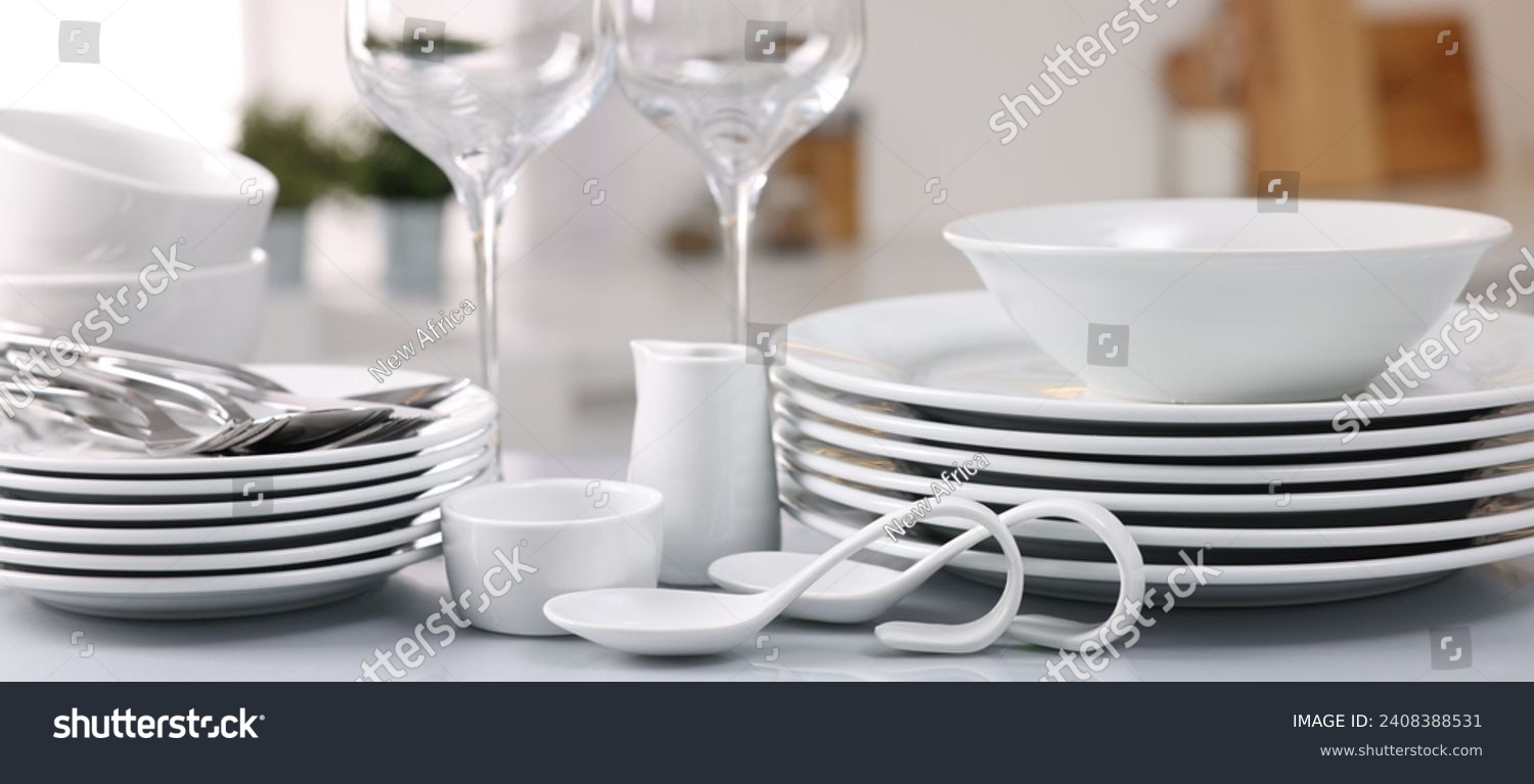 Set of clean dishware, glasses and cutlery on table in kitchen #2408388531