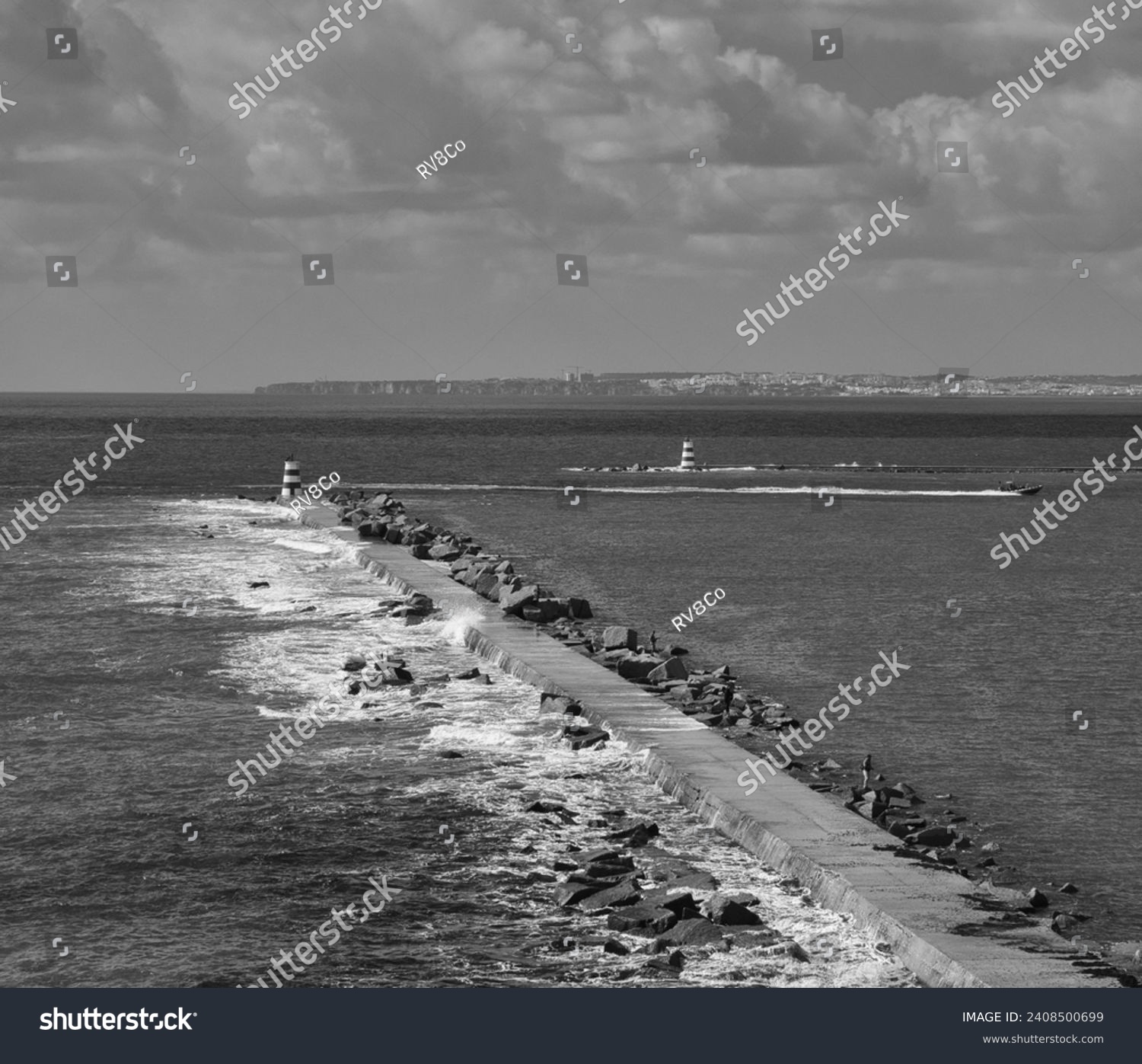 Motor boat entry into the seaport sailing the Arade River in Portimão. Sea waves hitting the protective rocks of the harbor. Black and white photography. #2408500699