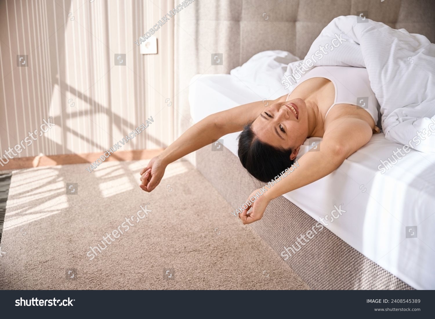 Merry lady enjoying her morning wake-up in cozy bedchamber #2408545389