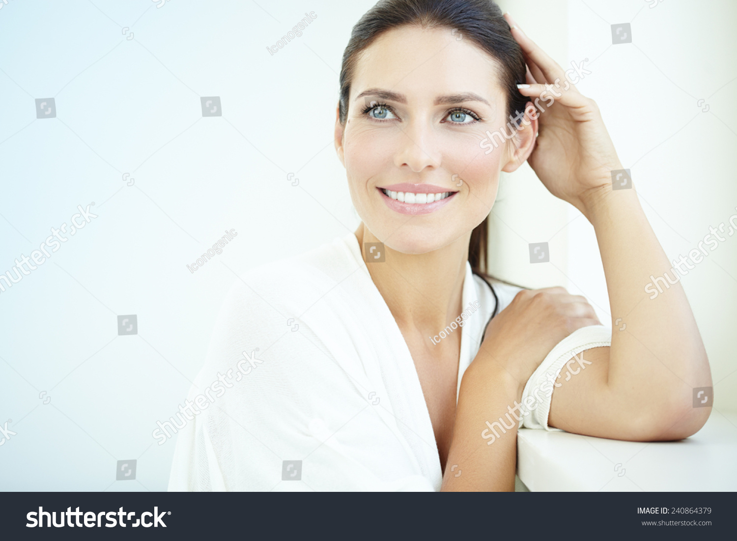 Smiling 30 year old woman at the window. Fresh light blue background. #240864379