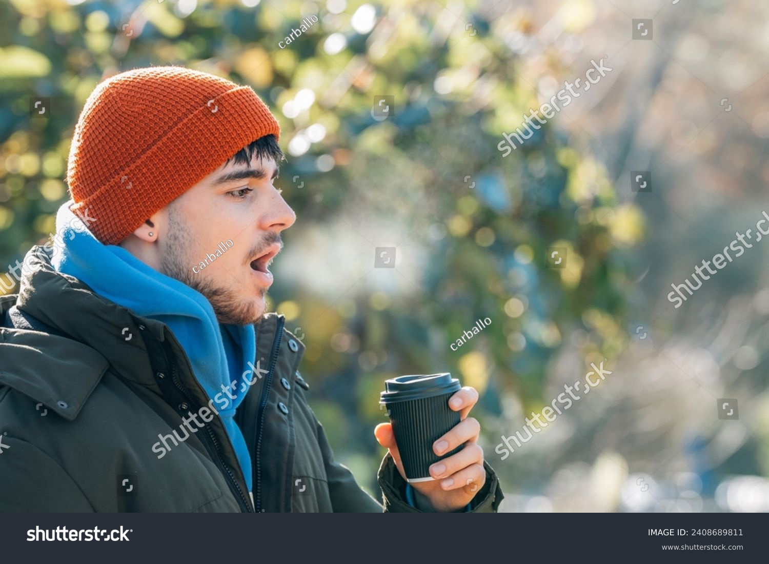 young man wrapped up in winter breathing halo of cold #2408689811