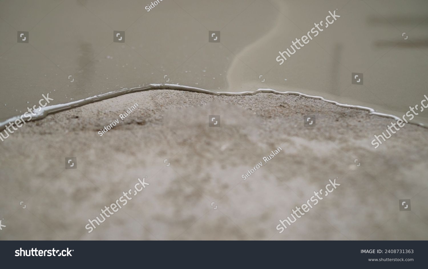 Self-leveling floor on a concrete surface close-up. Partial covering of the floor with self-leveling cement mortar. Self-leveling mixture for repairing floors in an apartment. #2408731363