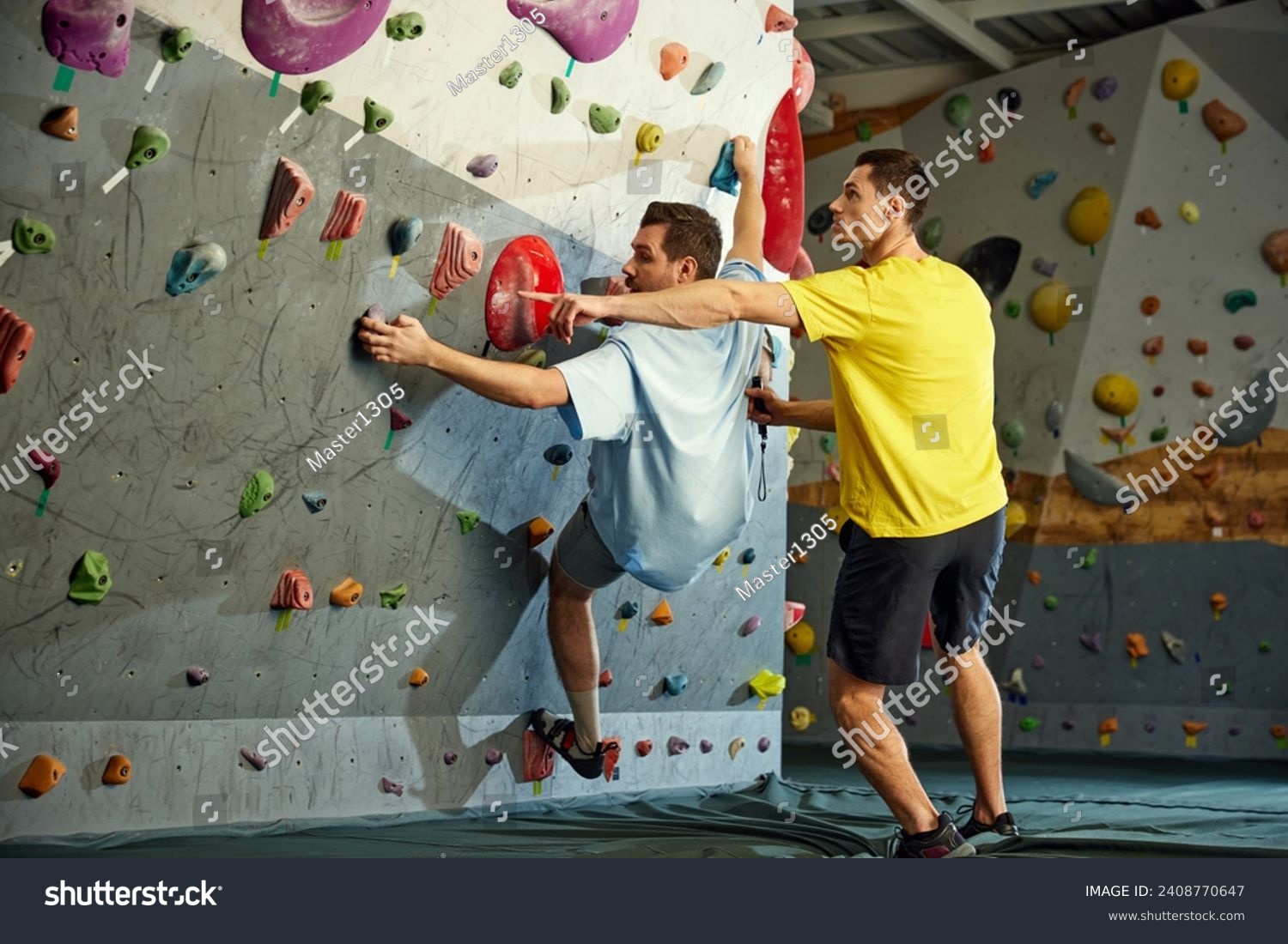 Male instructor teaching man to climb artificial wall. Man training, climbing up the artificial stones. Bouldering activity. Concept of sport, sport climbing, hobby, active lifestyle, school, course #2408770647