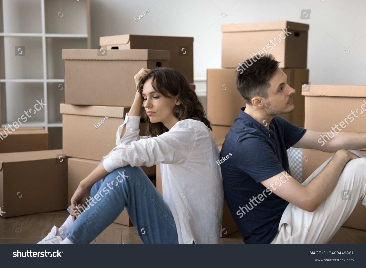 Sad tired married couple moving out from common flat, house, sitting back to back at stack of relocation boxes, looking away, keeping ignoring, thinking on divorce, finance problems, mortgage default #2409449861