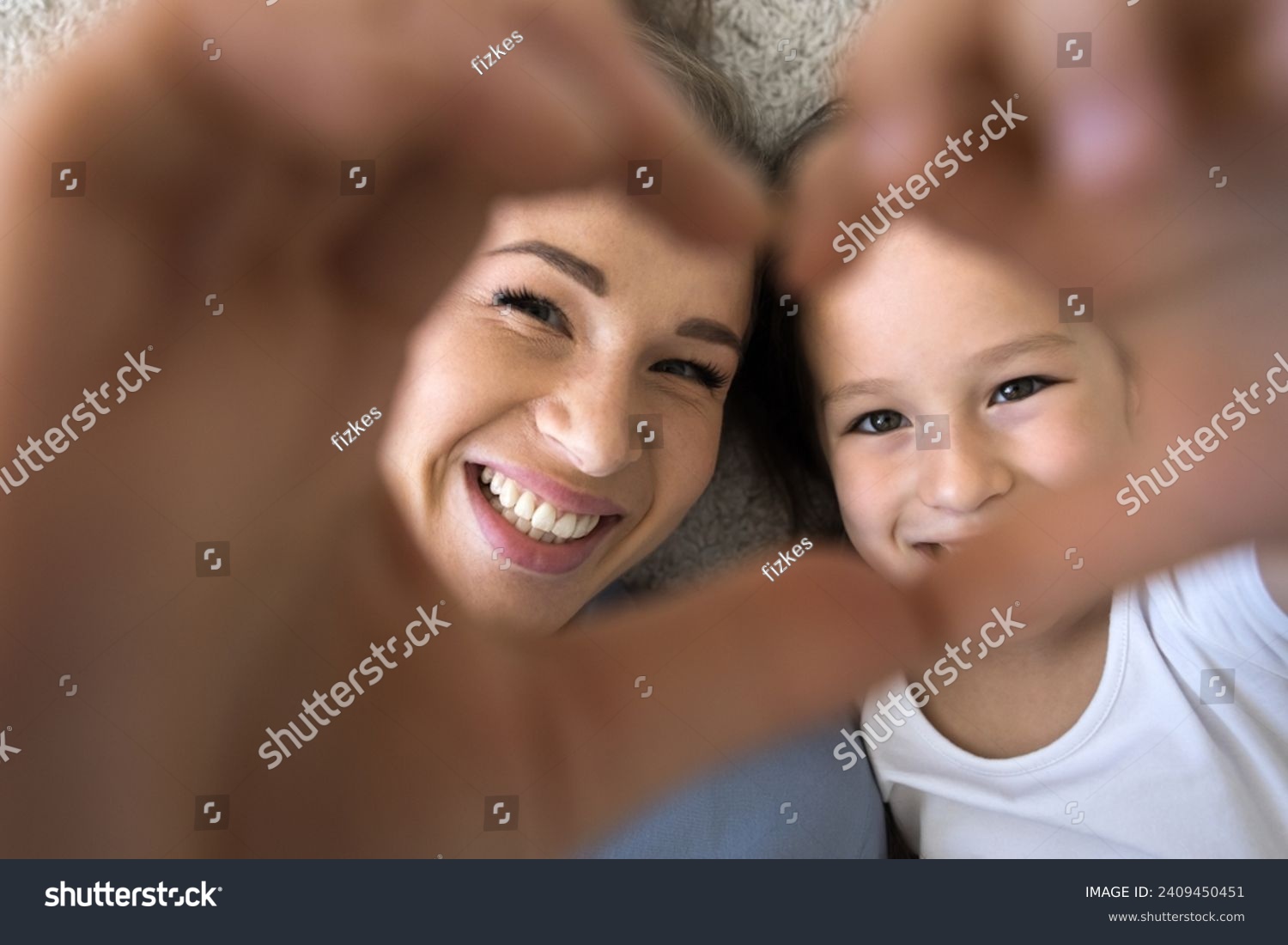 Close up shot daughter and loving mom showing symbol of affection, join fingers together look at camera through heart sign, feeling unconditional love, express support. Family ties, happy Mothers Day #2409450451