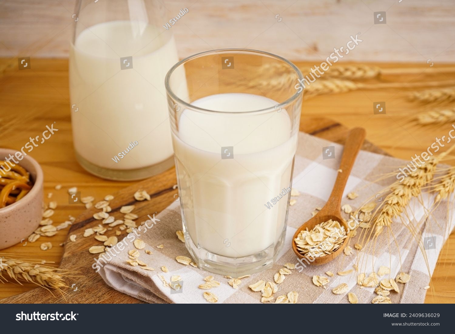 Glass and jug of fresh milk on wooden table against color background, with oatmeal. #2409636029