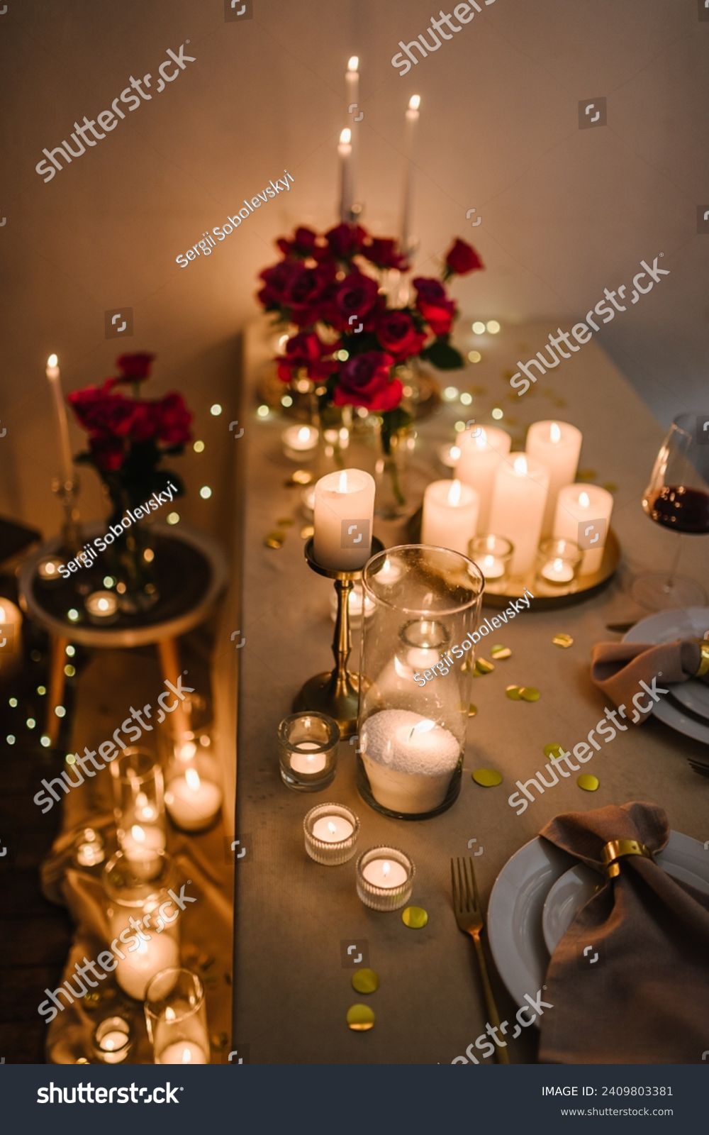 Romantic dinner setup at night. Wine glasses, flowers. Table setting for couple, Valentine's Day evening, burning candles for surprise marriage proposal. Candle light date in restaurant. Top view #2409803381
