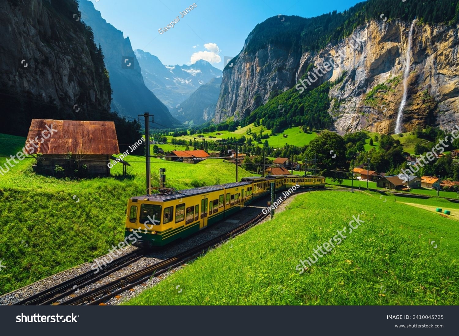 Amazing travel experience, modern electric cogwheel passenger train and Lauterbrunnen village with high waterfalls in background, Lauterbrunnen valley, Bernese Oberland, Switzerland, Europe #2410045725