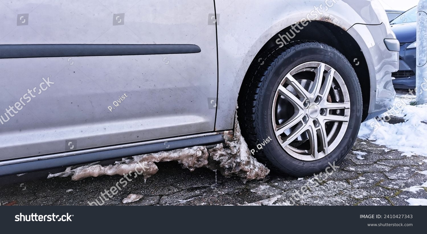 Dirty ice and snow build up in the wheel arch of a car in a freezing cold winter #2410427343