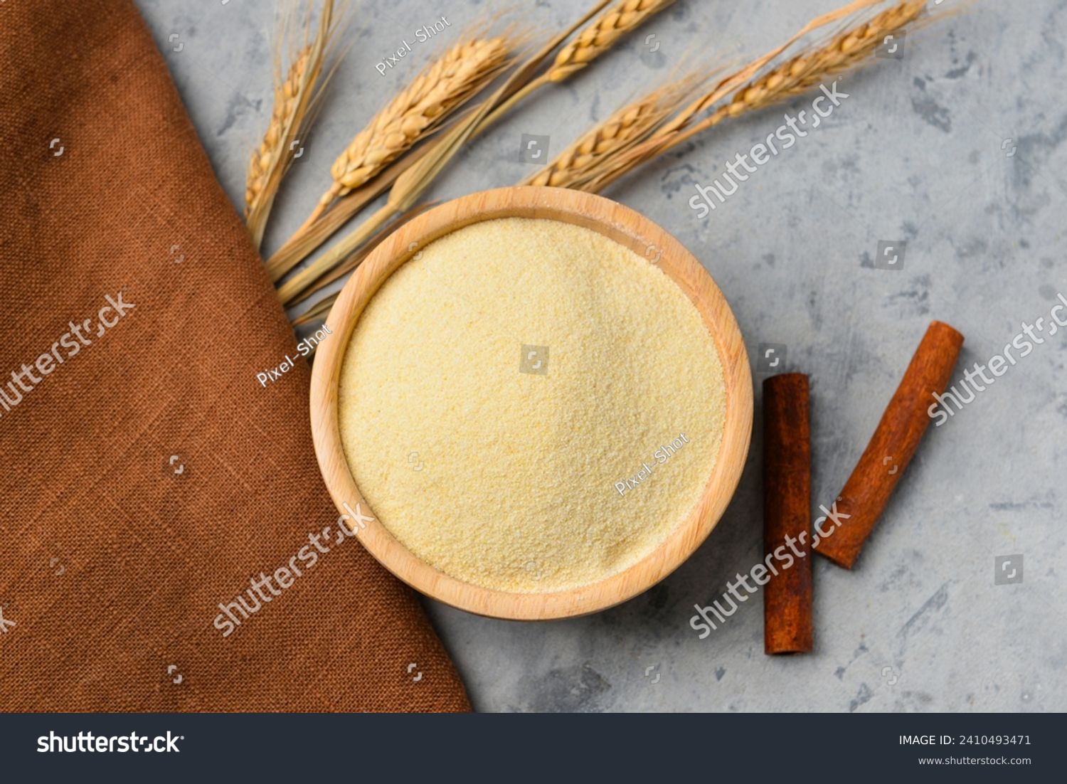 Bowl of raw semolina, cinnamon and spikelets on grunge background #2410493471
