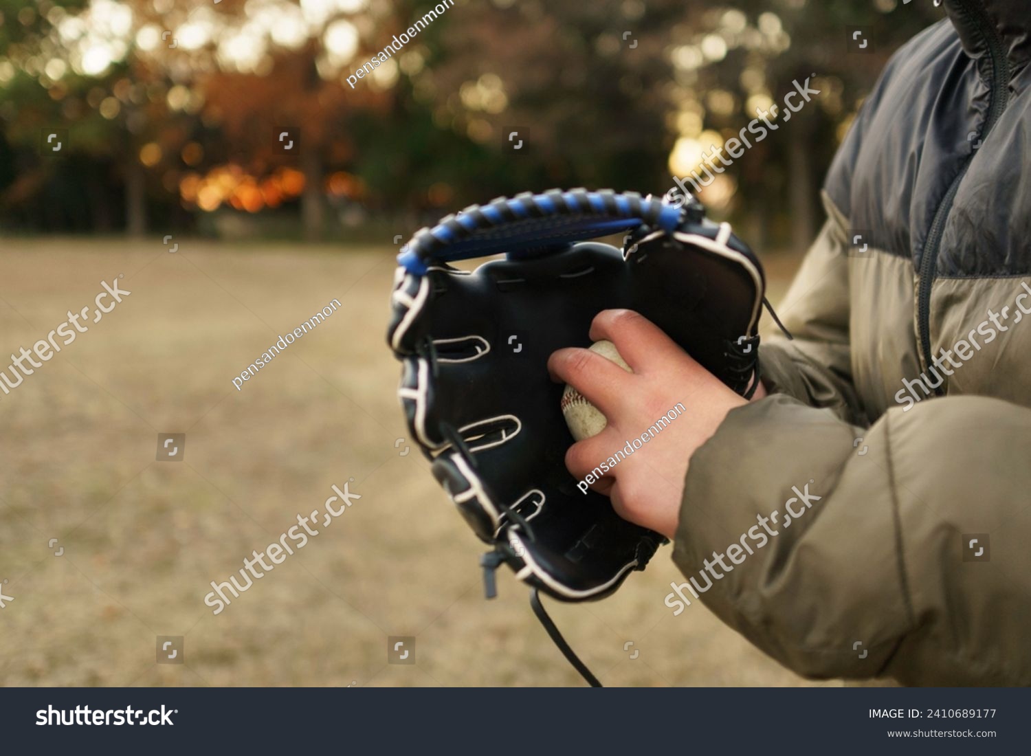 A boy holding a ball, before throwing it. Baseball glove. Left handed. Grass Baseball, vacation, sports, practice, park, afternoon.  Fall or Winter, beginner pitcher. #2410689177