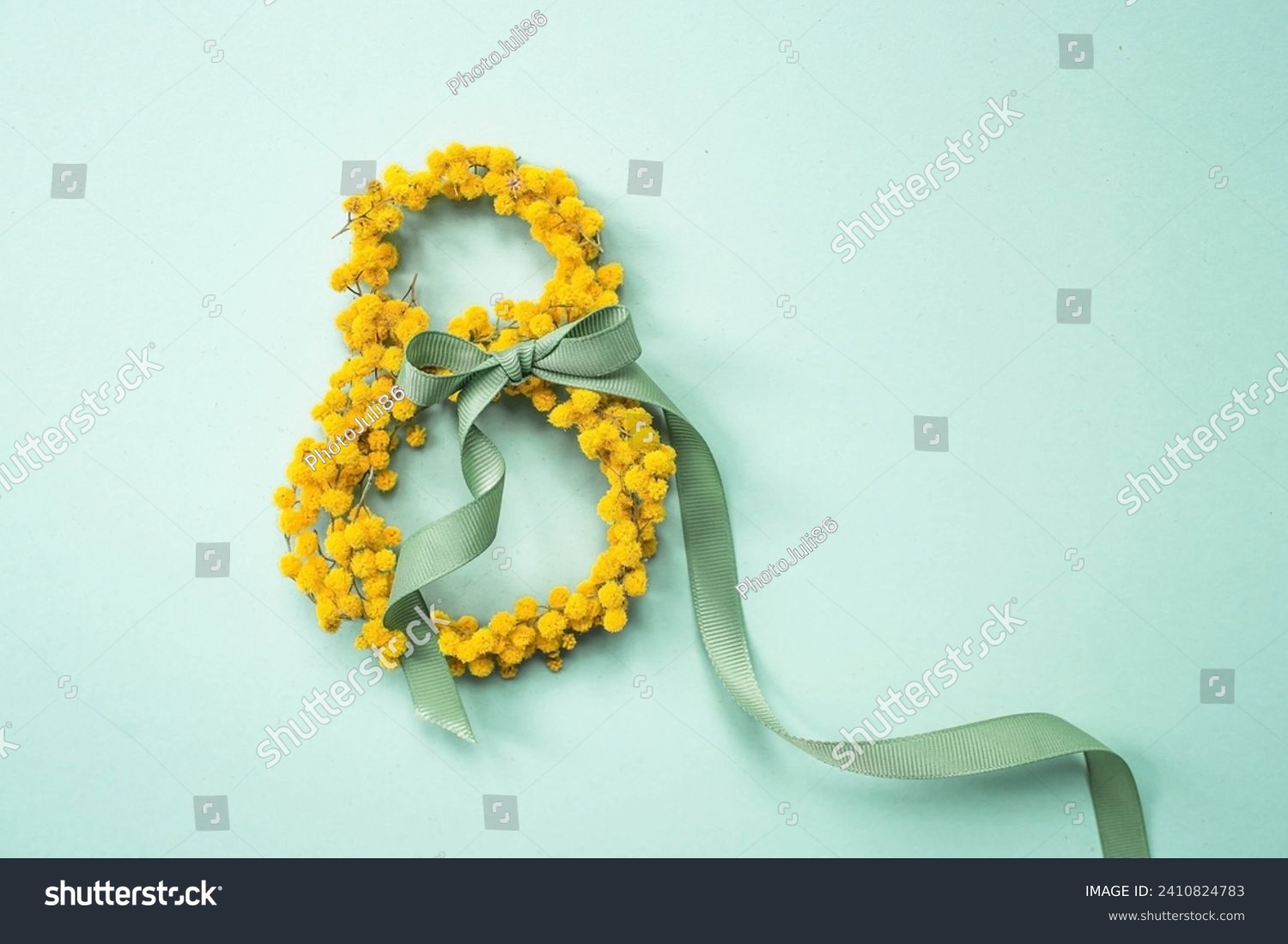 International Women's Day. A banner, a flyer, a beautiful postcard for March 8th. Yellow mimosa flowers in the shape of the number eight and a ribbon bow on a turquoise, blue background. #2410824783
