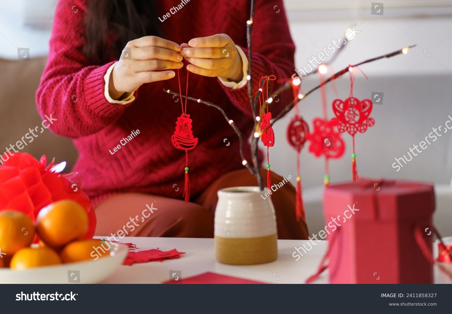 Asian Woman decorated house for Chinese New Year Celebrations. putting traditional pendant to the Chinese Lunar New Year for good luck. Chinese word means blessing. #2411858327