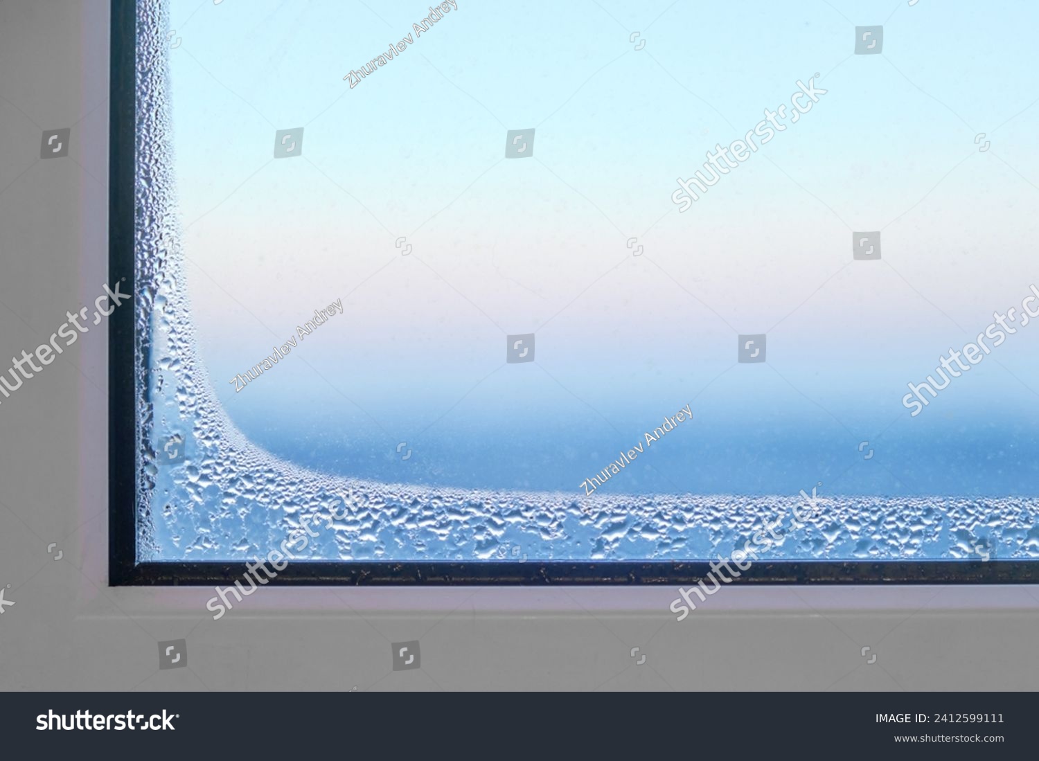 Foggy window glass covered with ice freezes indoors during severe frosts. Frozen defective plastic window in a room in winter. #2412599111