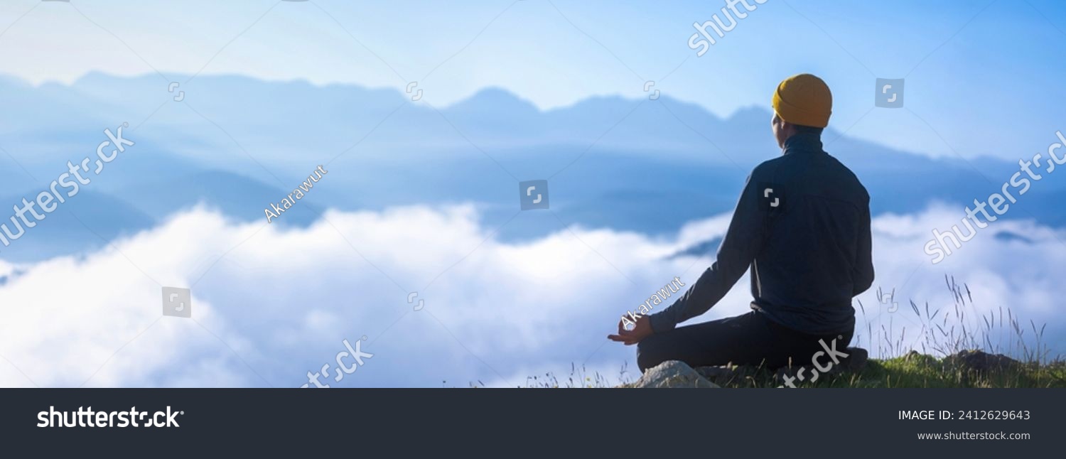 Panorama back view of man is relaxingly practicing meditation yoga mudra at mountain top with mist and fog in summer to attain happiness from inner peace wisdom for healthy mind and soul #2412629643