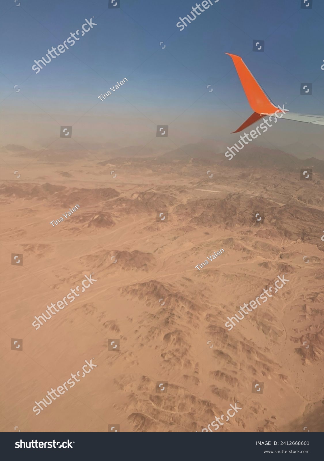 A photo of the airplane wing with the orange winglet during the flight above the desert #2412668601