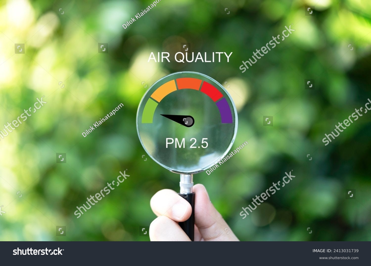 Hand holding magnifier glass with good air quality indicator scale on greenery background which check PM 2.5 or particulate matter 2.5 micron for air pollution effect to health and lifestyle concept. #2413031739