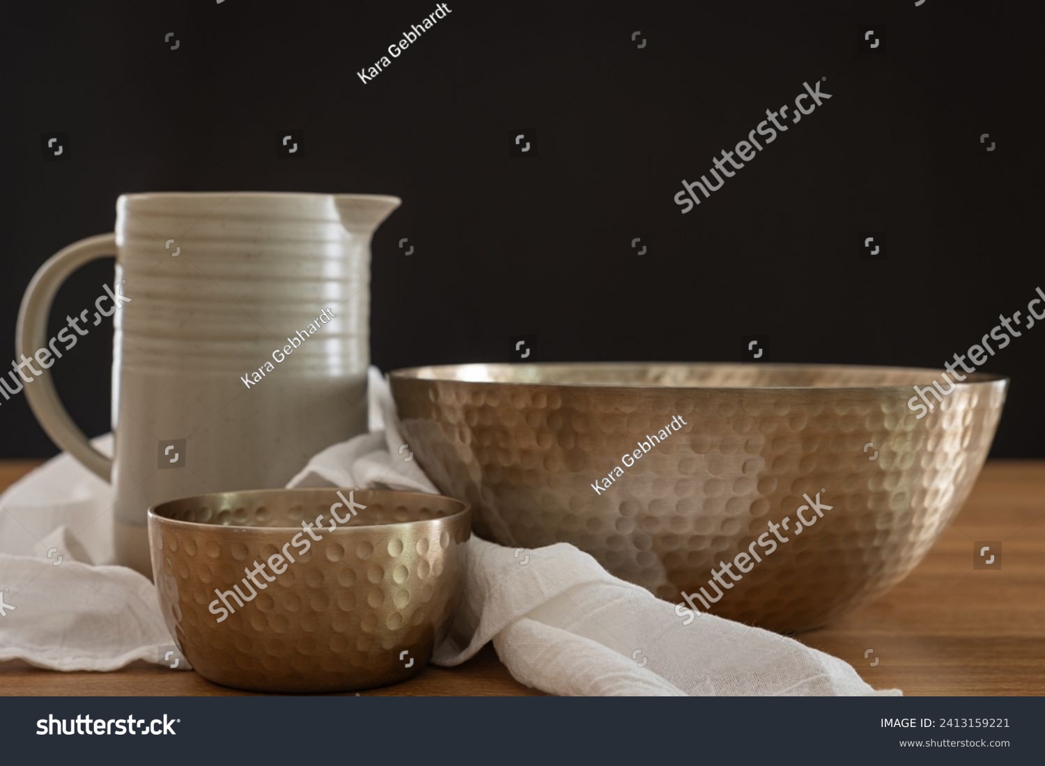Clay pitcher, two copper bowls and white linen with a black background and copy space #2413159221