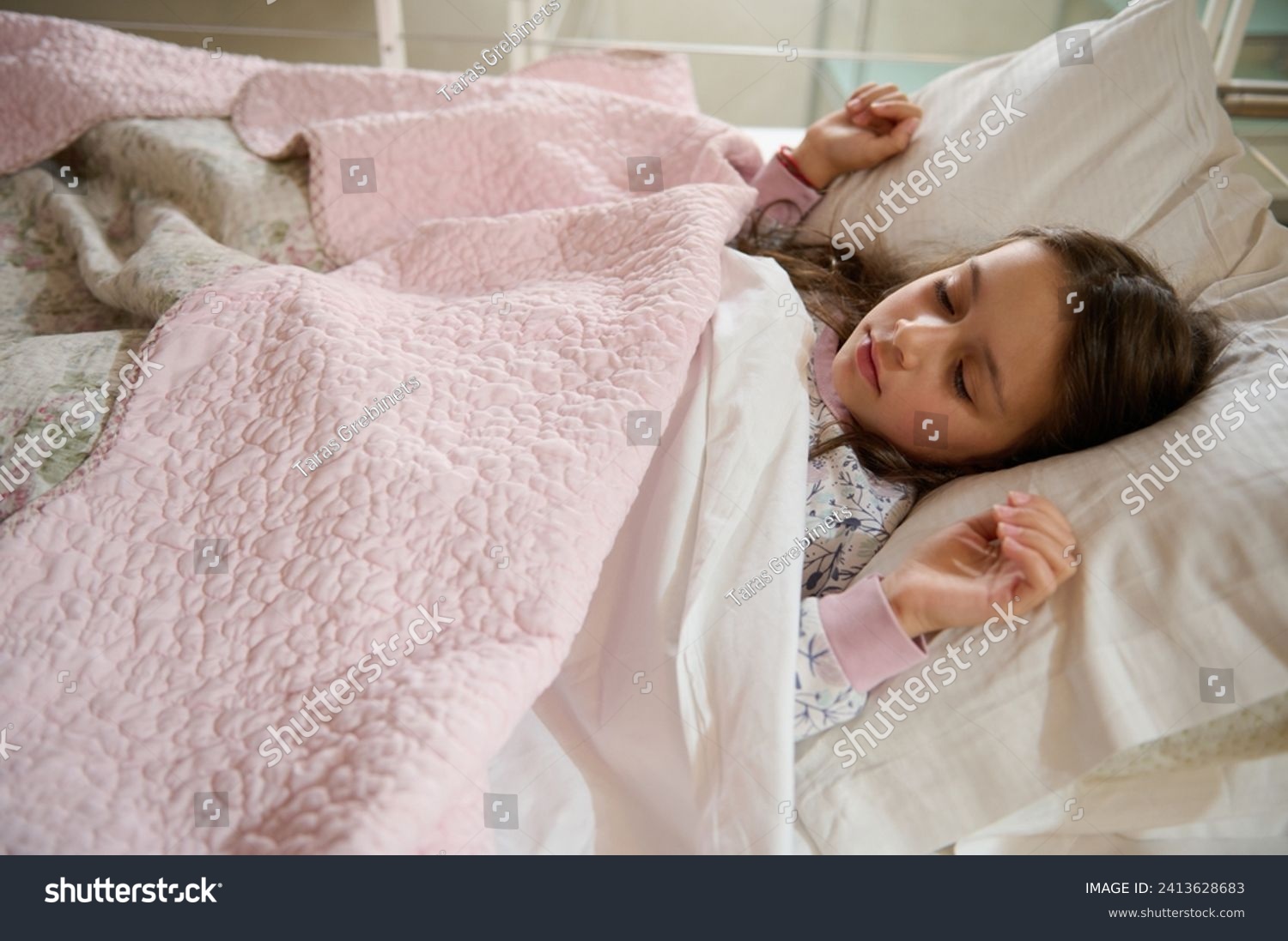 Authentic portrait of Caucasian elementary age, a cute little kid girl seeing sweet dreams while sleeping on the bed with comfortable mattress. Bedtime. Bedchamber furniture. Happy carefree childhood #2413628683