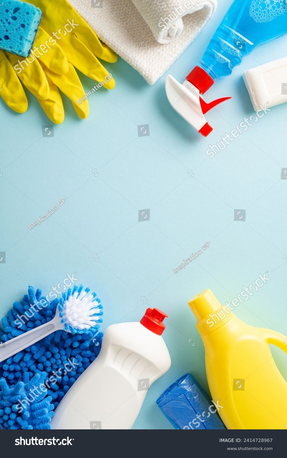A clean sweep in aesthetics. Top view vertical photo featuring cleaning essentials—rags, gloves, and detergent bottles—arranged on calming pastel blue background. Adaptable space for text or branding #2414728967