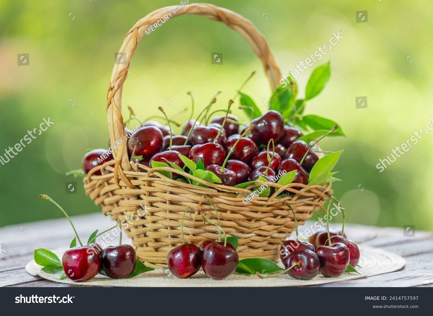 Red Cherry fruit in wooden basket on wooden table in garden, Red Cherry on blurred greenery background. #2414757597