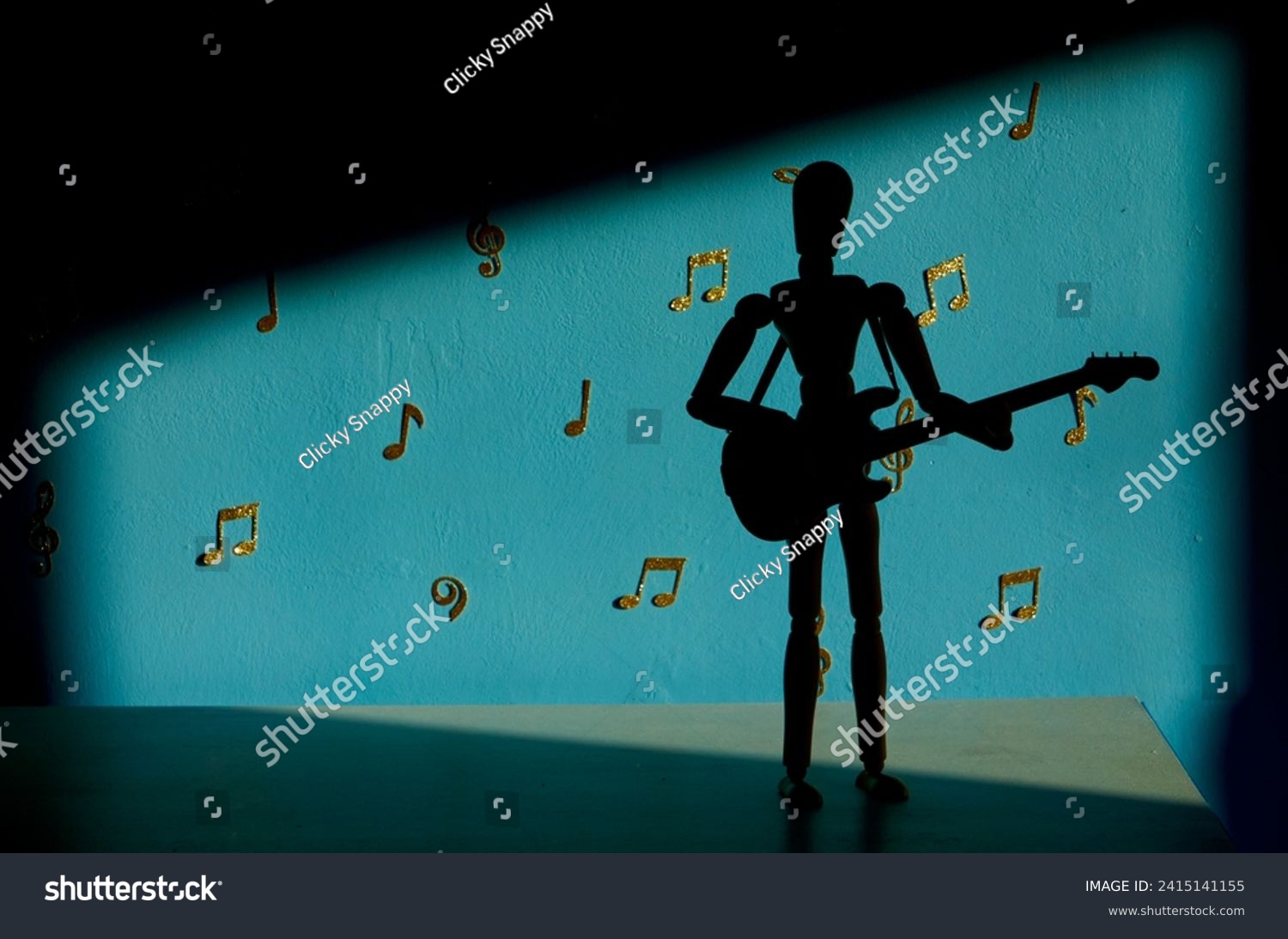 A 12 inch wooden drawing mannequin figure silhouette plays a bass guitar against a blue backdrop with gold musical notes and treble and bass clefs #2415141155