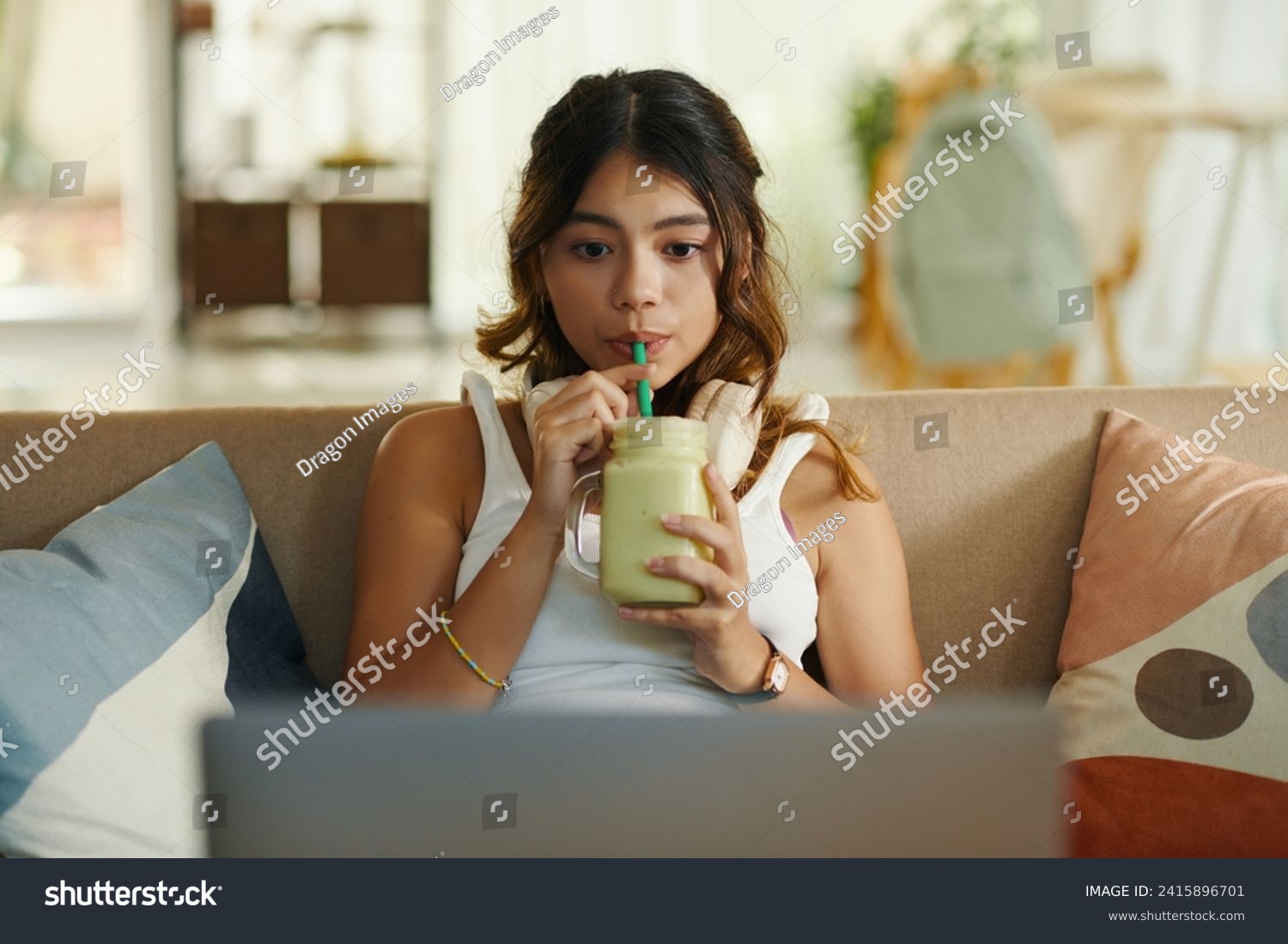 Zoomer girl sipping smoothie and and watching show on laptop #2415896701