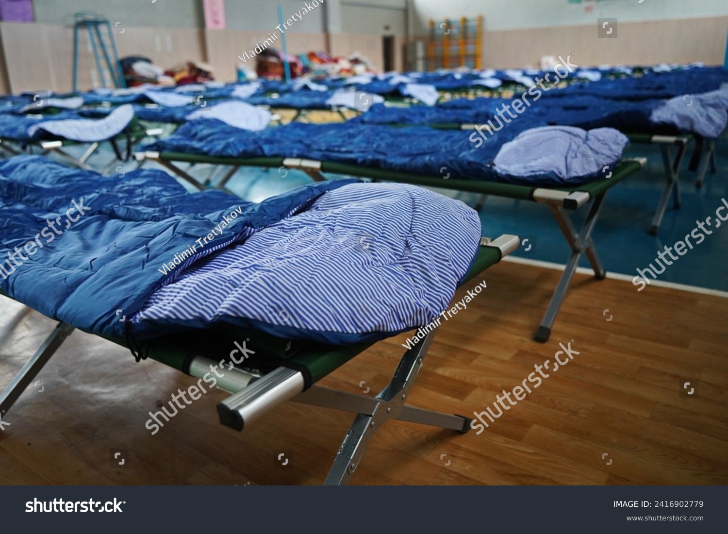 Cots with sleeping bags are placed in the school gym during an emergency #2416902779