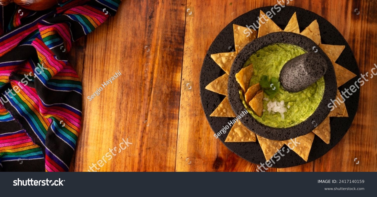 Guacamole. Avocado dip with tortilla chips also called Nachos served in a bowl made with volcanic stone mortar and pestle known as molcajete. Mexican easy homemade sauce recipe very popular. #2417140159
