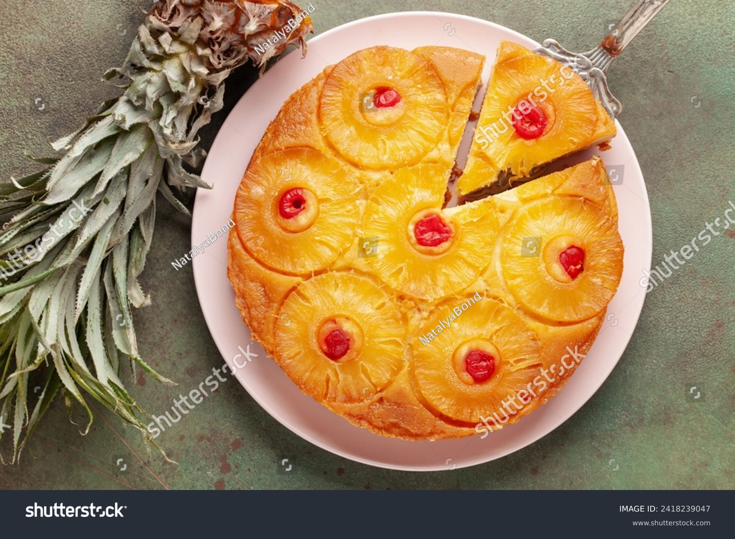 Homemade pineapple upside down pie with candied cherries . Tropical dessert on green background. Top view #2418239047