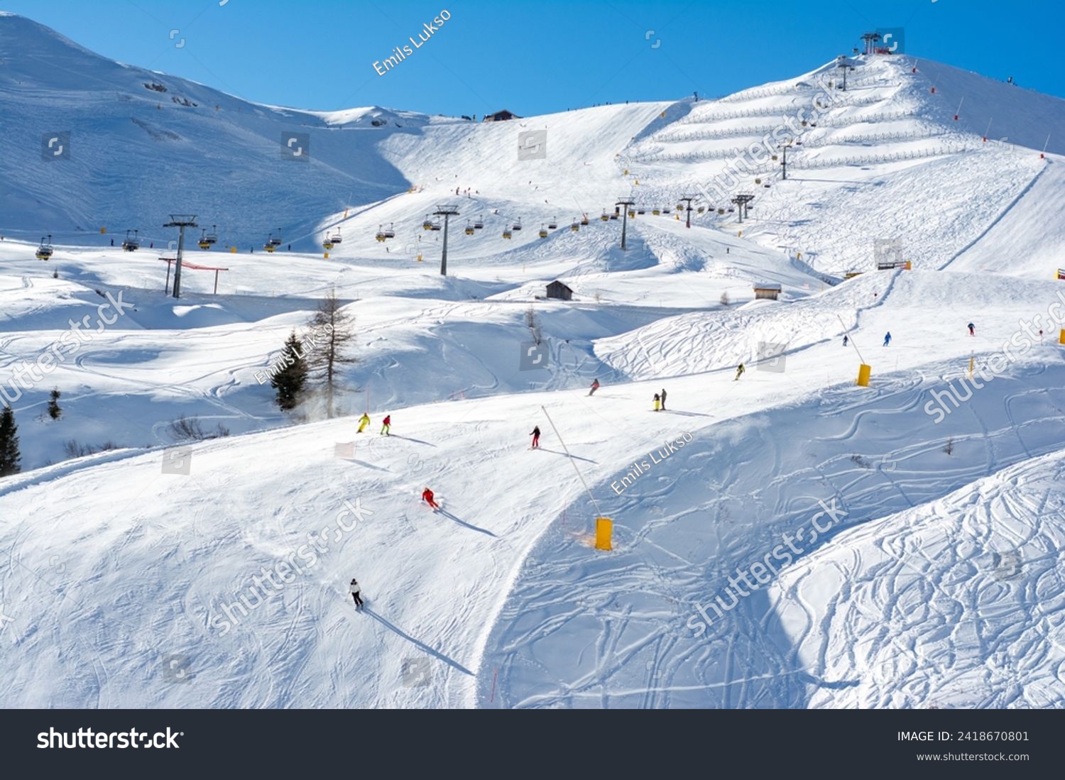 Ski resort in the Dolomites. Mountain recreation place. Ski slopes in the Dolomites on a clear sunny day. Alpine skiing sport and recreation. #2418670801