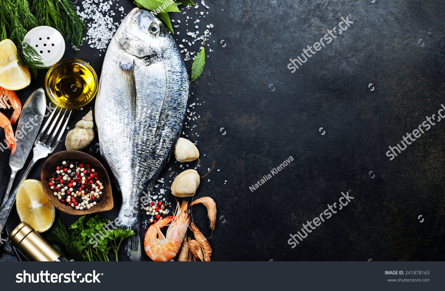 Delicious fresh fish on dark vintage background. Fish with aromatic herbs, spices and vegetables - healthy food, diet or cooking concept  #241878163
